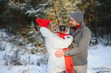 Sevgi dolu bir çift, karlı bir ormanın arka planında yürür. Bir adam bir köpek tutuyor. Beyaz ceketli ve kırmızı şapkalı bir kız..