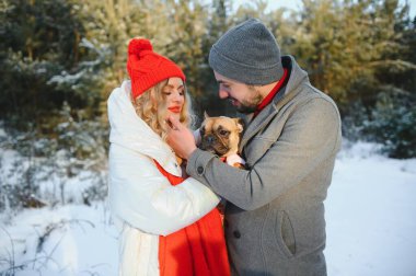Sevgi dolu bir çift, karlı bir ormanın arka planında yürür. Bir adam bir köpek tutuyor. Beyaz ceketli ve kırmızı şapkalı bir kız..