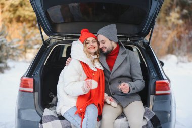 Birlikte gülümsüyoruz. Güzel bir çift kışın kırda bir hafta sonu geçirir. Modern arabanın arka tarafında oturuyor..