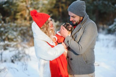 Sevgi dolu bir çift, karlı bir ormanın arka planında yürür. Bir adam bir köpek tutuyor. Beyaz ceketli ve kırmızı şapkalı bir kız..