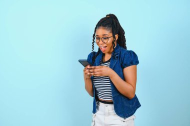 Mutlu Afro-Amerikan kadın ekranda akıllı telefonlara bakıyor. İnternette sohbet etmekten hoşlanıyor. Kısa mesajlar, sosyal ağlarda geziniyor. Teknoloji konsepti