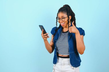Mutlu Afro-Amerikan kadın ekranda akıllı telefonlara bakıyor. İnternette sohbet etmekten hoşlanıyor. Kısa mesajlar, sosyal ağlarda geziniyor. Teknoloji konsepti