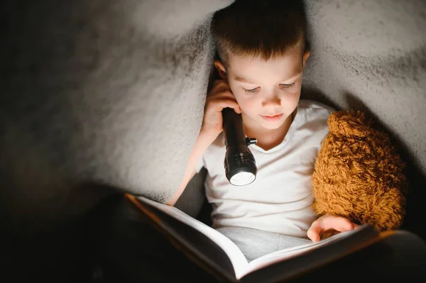 Хлопчик Років Читає Книгу Ввечері Темряві Під Ковдрою Іграшковим Ведмедем — стокове фото