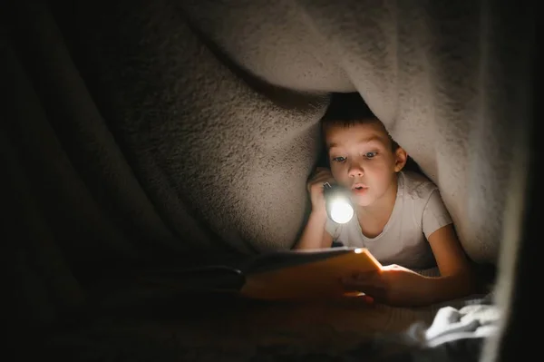 Läsa Bok Och Använda Ficklampa Ung Pojke Avslappnade Kläder Liggande — Stockfoto