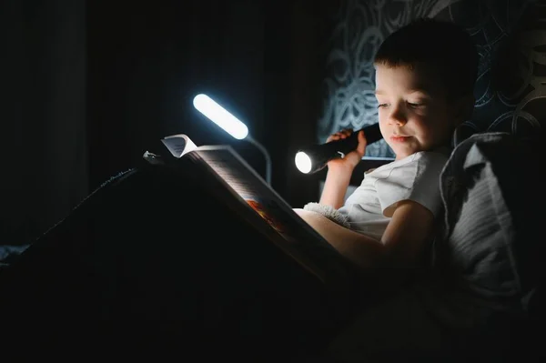 Läsa Bok Och Använda Ficklampa Ung Pojke Avslappnade Kläder Liggande — Stockfoto