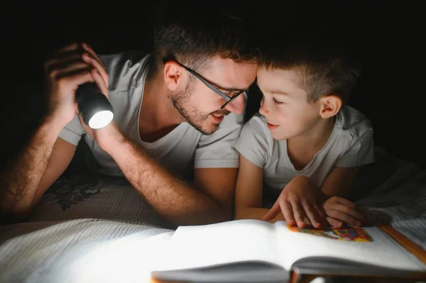 Far Och Son Med Ficklampa Läsa Bok Filt Hemma — Stockfoto