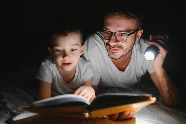 Vater Und Sohn Mit Taschenlampe Lesebuch Unter Decke Hause — Stockfoto