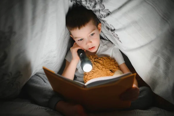 Хлопчик Років Читає Книгу Ввечері Темряві Під Ковдрою Іграшковим Ведмедем — стокове фото