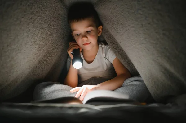 Läsa Bok Och Använda Ficklampa Ung Pojke Avslappnade Kläder Liggande — Stockfoto