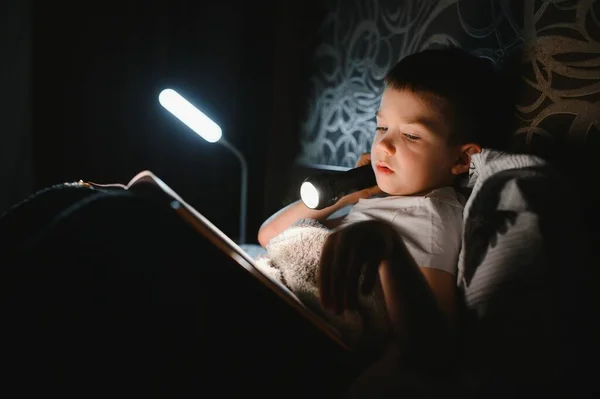 Портрет Милий Маленький Хлопчик Читає Ліжку Ліхтариком Темній Кімнаті Насолоджуючись — стокове фото