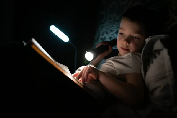 Kitap Okumak Feneri Kullanmak Gündelik Giysiler Içinde Genç Bir Çocuk — Stok fotoğraf