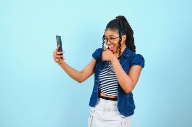 Mutlu Afro-Amerikan kadın ekranda akıllı telefonlara bakıyor. İnternette sohbet etmekten hoşlanıyor. Kısa mesajlar, sosyal ağlarda geziniyor. Teknoloji konsepti