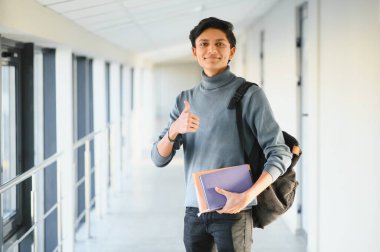 Elinde kitap tutan Hintli üniversiteli çocuğun portresi..