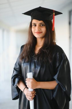 Mezuniyet elbisesi ve şapkası içinde diploması olan mutlu Hintli üniversite öğrencisi..