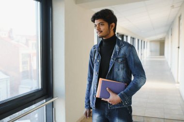 Elinde kitap tutan Hintli üniversiteli çocuğun portresi..