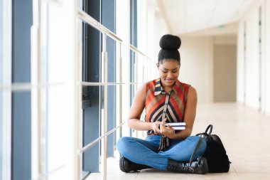 Eğitim, lise, üniversite, öğrenme ve Afrika kökenli Amerikalı öğrenci kız okuma kitap Kütüphanesi'nde merdivenlerde oturan gülümseyen insanlar kavramı-