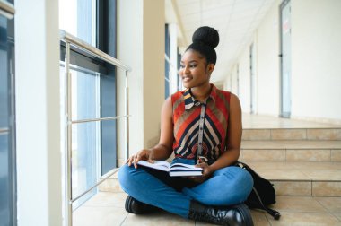Sırt çantalı, üniversite geçmişinde gülümseyen Afro-Amerikan öğrenci kız. Teknoloji, eğitim, eğlence kavramı