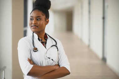 Dost canlısı, güler yüzlü, laboratuvar önlüklü, steteskoplu, kendine güvenen bir kadın sağlık uzmanı portresi. Tecrit edilmiş bir klinik geçmişi var. Ofis ziyareti zamanı.