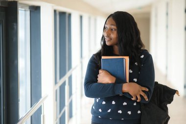 Üniversite sınıfında sırt çantası ve evrak işleriyle uğraşan Afro Amerikalı güzel bir bayan öğrenci.