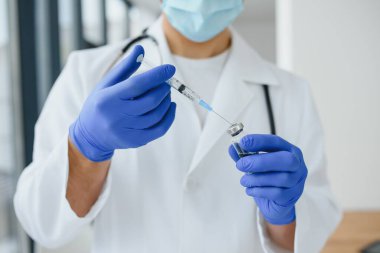 PPE 'deki doktor elinde Coronavirus Covid 19 yeni Omicron çeşidine karşı bir şişe ya da şişe aşısı tutuyor. SARS-CoV-2 salgınına bağlı aşı, deneme ve tedavi kavramı