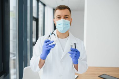 PPE 'deki doktor elinde Coronavirus Covid 19 yeni Omicron çeşidine karşı bir şişe ya da şişe aşısı tutuyor. SARS-CoV-2 salgınına bağlı aşı, deneme ve tedavi kavramı