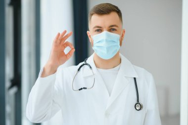 Cerrahi maske takan erkek doktorun portresi Coronavirüs veya covid virüsü olan hastalara yardım etmeye hazır..