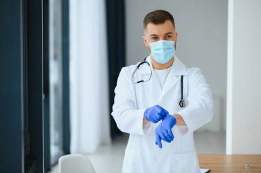 Cerrahi maske takan erkek doktorun portresi Coronavirüs veya covid virüsü olan hastalara yardım etmeye hazır..