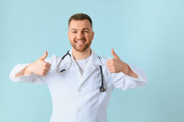 Gülümseyen mutlu doktorun belden yukarı portre görüntüsü mavi arka plandaki boş alana parmağını gösteriyor. Doktor ve tıp konsepti