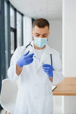 PPE 'deki doktor elinde Coronavirus Covid 19 yeni Omicron çeşidine karşı bir şişe ya da şişe aşısı tutuyor. SARS-CoV-2 salgınına bağlı aşı, deneme ve tedavi kavramı