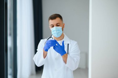 Cerrahi maske takan erkek doktorun portresi Coronavirüs veya covid virüsü olan hastalara yardım etmeye hazır..