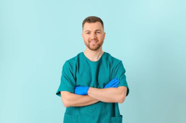 Boynunda steteskop olan genç sakallı doktor mavi arka plana karşı duruyor..