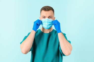 Tıbbi üniformalı yakışıklı erkek doktor covid-19 virüsüne karşı koruyucu maske takmış. Coronavirus koruması, sağlık hizmetleri, tıbbi ekipmanlar