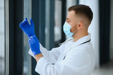 Cerrahi maske takan erkek doktorun portresi Coronavirüs veya covid virüsü olan hastalara yardım etmeye hazır..
