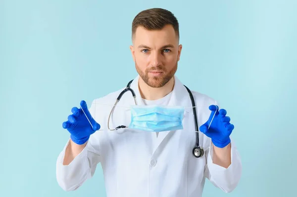 Man Medische Handschoenen Zet Beschermende Gezichtsmasker Tegen Blauwe Achtergrond — Stockfoto