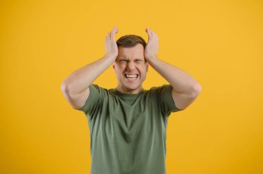 Kafasını elleriyle tutan genç bir adamın portresi. Umutsuzluk ve umutsuzluk kavramı. Hayal kırıklığı. Migren.