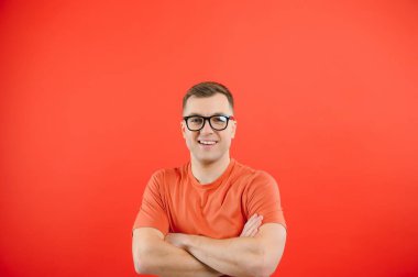 Gündelik kıyafetler ve gözlük takan genç bir adam. Mutlu ve havalı bir gülümsemesi var. şanslı kişi.