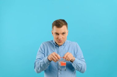 Mavi arka planda küçük bir alışveriş arabası tutan gülümseyen genç adam. Satış konsepti. Metin için yer.