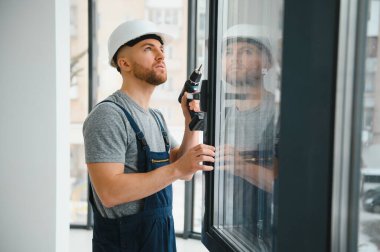 İnşaat işçisi plastik pencereyi tornavidayla tamir ediyor. Pankart tasarımı