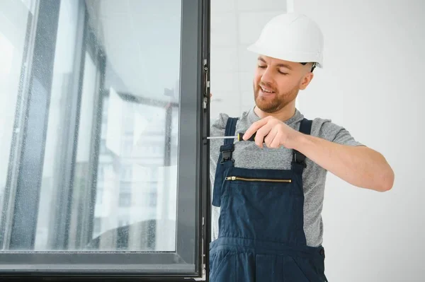 Byggarbetare Reparerar Plastfönster Med Skruvmejsel Inomhus Utrymme För Text Banderolldesign — Stockfoto
