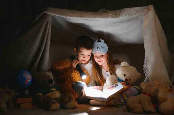 Feneri Olan Iki Çocuk Battaniyenin Altında Çadır Olarak Kitap Okudu — Stok fotoğraf