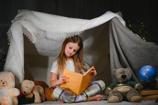 ランプの下の床に本を読んでいるかなり小さな女の子 子供と教育 — ストック写真