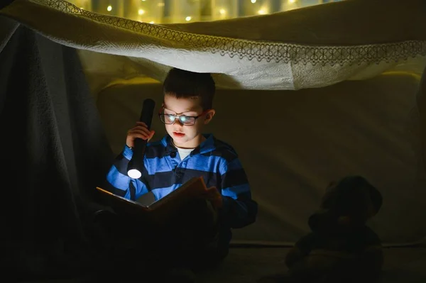 Хлопчик Ліхтариком Читає Книгу Вдома — стокове фото