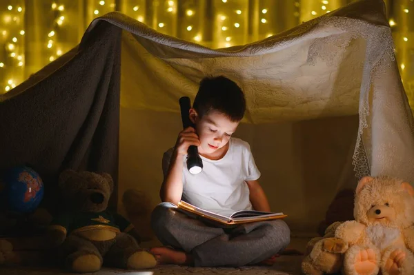 Хлопчик Ліхтариком Читає Книгу Вдома — стокове фото