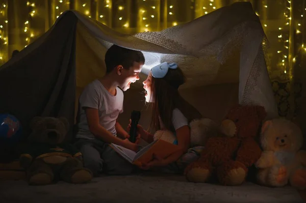 子供の男の子と女の子は夜にテントの中で懐中電灯で遊んだり怖がらせたり — ストック写真