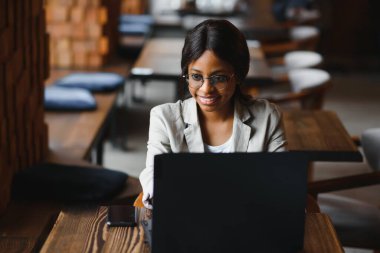 Mutlu Afrikalı Amerikan kadın işçisi Loft ofis veya kafede bilgisayarda dizüstü çalışma çalışması kullanarak, gülümseyen karışık yarış kadın öğrenci Freelancer kullanarak PC uygulaması dating iletişim çevrimiçi izleme Webinar