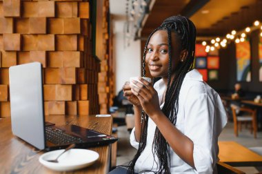 Siyah bayanın sabah kahvesinin keyfini çıkarırken ve e-postaları dizüstü bilgisayardan, kafenin içinden, boş alandan kontrol ederken yan görüntüsü