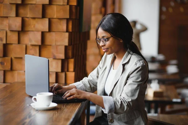 Focused young african american businesswoman or student looking at laptop, serious black woman working or studying with computer doing research or preparing for exam online