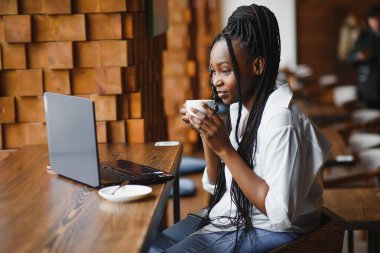Siyah bayanın sabah kahvesinin keyfini çıkarırken ve e-postaları dizüstü bilgisayardan, kafenin içinden, boş alandan kontrol ederken yan görüntüsü