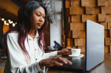 Mutlu Afrikalı Amerikan kadın işçisi Loft ofis veya kafede bilgisayarda dizüstü çalışma çalışması kullanarak, gülümseyen karışık yarış kadın öğrenci Freelancer kullanarak PC uygulaması dating iletişim çevrimiçi izleme Webinar