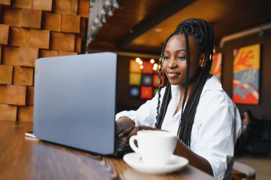 Mutlu Afrikalı Amerikan kadın işçisi Loft ofis veya kafede bilgisayarda dizüstü çalışma çalışması kullanarak, gülümseyen karışık yarış kadın öğrenci Freelancer kullanarak PC uygulaması dating iletişim çevrimiçi izleme Webinar